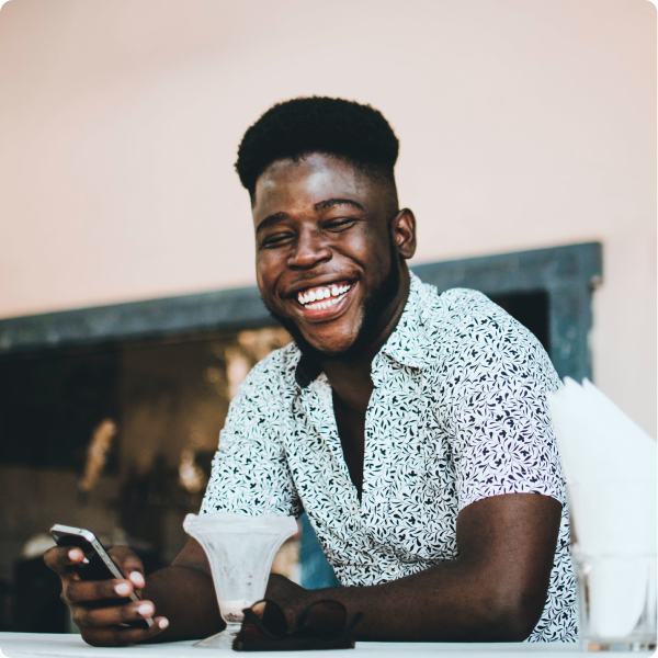 Health Loft dietitians for autoimmune disease nutrition Young man smiling while holding his phone and having coffee